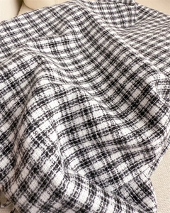 Close-up of black and white plaid tweed fabric showing detailed woven fiber textures