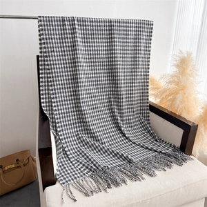 Classic black and white checkered scarf featuring woven tassel edges draped on a white chair