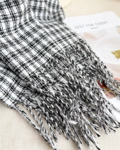 Close-up of black and white plaid scarf featuring classic woven texture and long tassels