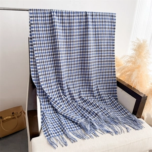 Detail of blue and brown checkered scarf with long tassels on a minimalist chair