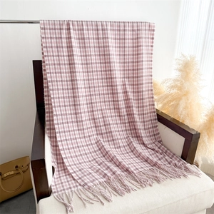 Detail of pink and white plaid scarf with soft fringes on a cozy armchair