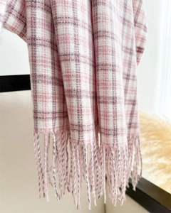 Detailed view of pink and white plaid scarf with soft texture and tassel edges