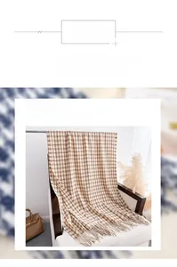 Gros plan sur l'écharpe pied-de-poule beige et marron avec pompons sur fauteuil