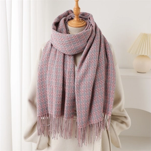 Détail d'une écharpe pied-de-poule rose et gris avec de longues franges sur un tissu doux