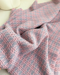 Gros plan d'une écharpe pied-de-poule rose et grise avec texture tricotée et détails de tissage