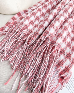 Détail de l'écharpe en pied-de-poule rouge et blanc avec des pompons faits à la main