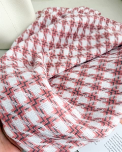 Détail de la texture douce du cachemire pied-de-poule avec motifs ondulés rose et gris