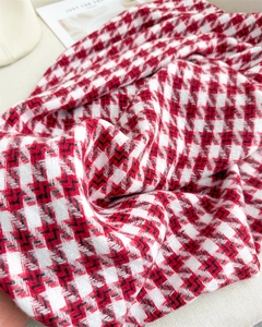 Gros plan sur le motif pied-de-poule rouge et blanc du châle doux à franges