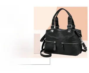 Detail of black textured faux leather handbag showing silver hardware and tassel zippers