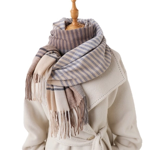 Thick color-block striped scarf with long tassels draped over a white wool coat