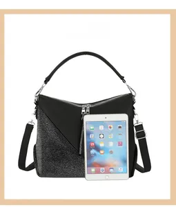 Detail of hobo handbag with sparkling rhinestone accents and fringe zippers next to an iPad