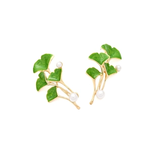 Detailed view of ginkgo leaf earrings with green enamel, gold trim and pearls