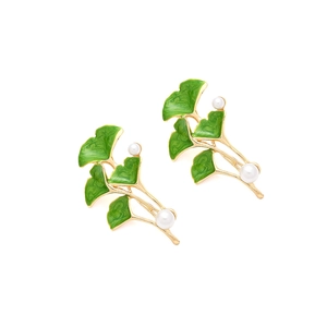 Detail view of ginkgo leaf earrings with green enamel coating and white imitation pearls