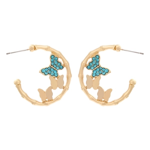 Golden bamboo C-shape earrings with blue crystals and butterfly insect motifs on white background