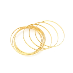 Macro view of stackable gold thin bangles showing frosted texture and hammered finish