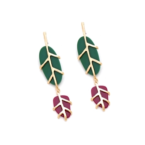 Detail of leaf-shaped earrings with green and purple resin petals and gold metal veins