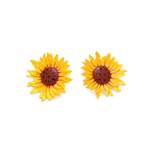 Détail macro de boucles d'oreilles tournesol avec pétales en émail jaune et centre brun