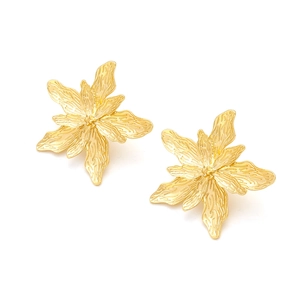 Dettaglio ravvicinato di orecchini vintage a forma di fiore dorato con petali opachi