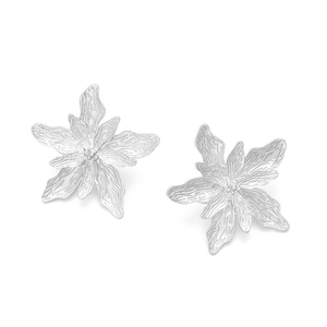 Dettaglio di orecchini a fiore in metallo argento con petali a strati e texture