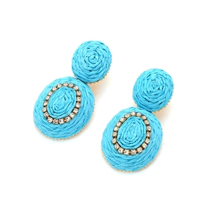 Detail of bright blue raffia earrings featuring woven texture and crystal-embellished oval drop