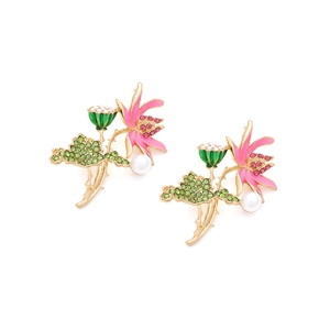 Macro shot of lotus earrings with pink enamel, green crystals, and a faux pearl detail