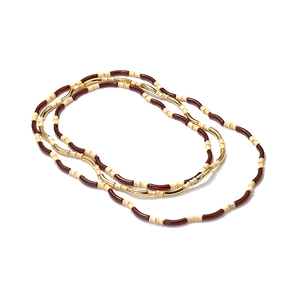 Detail of layered bohemian necklace with dark resin, gold metal tubes and cream beads
