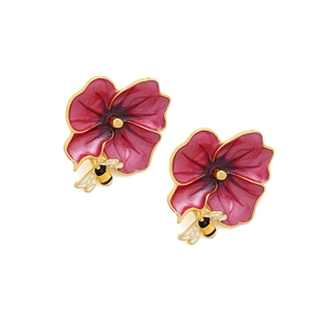 Close-up of enamel flower earrings with detailed bee motif and gold plating