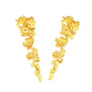 Gros plan de boucles d'oreilles pendantes fleurs et feuilles dorées au fini métal mat