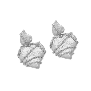 Close-up of silver hammered heart earrings with chain wrap detail on white background