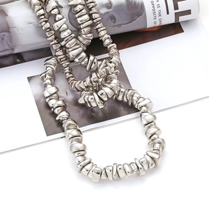 Irregular silver beaded multi-layered necklace with a polished metallic texture on a magazine