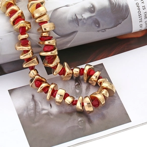 Bohemian luxury necklace with irregular golden beads and dark red resin stones on a magazine