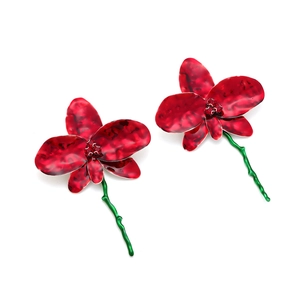 Détail macro de boucles d'oreilles orchidées en émail avec pétales bordeaux