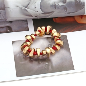 Bohemian beaded bracelet set with gold irregular metal blocks and red stones on a magazine