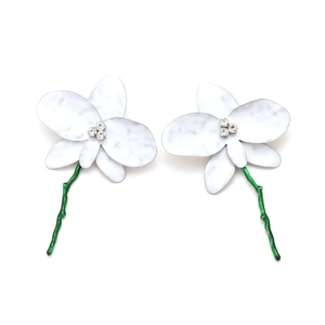 Détail de boucles d'oreilles orchidée blanche avec tiges vertes et strass brillants