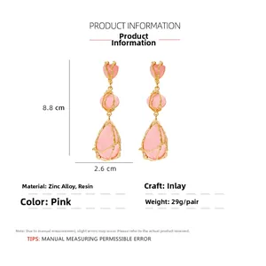Vue détaillée des boucles d'oreilles en résine rose avec cadre doré et taille 8,8 cm