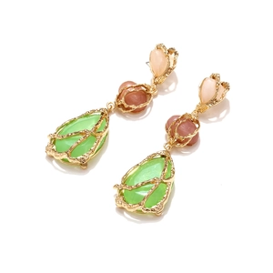 Détail de boucles d'oreilles en résine goutte avec cadre en métal doré texturé