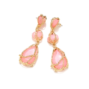 Détail de boucles d'oreilles pendantes en résine rose et alliage doré à texture brute