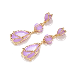 Détail de pierres gouttes en résine violette dans des cadres dorés à texture d'écorce fine