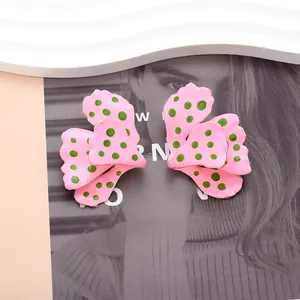 Detail von rosa Blumenohrringen mit grünen Punkten und Goldrand auf Magazin