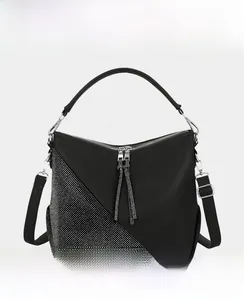 Detail of black PU leather handbag with silver studs and decorative tassels on zipper