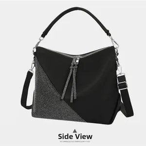 Detailed side view of black pebbled leather handbag with silver rhinestone tassels