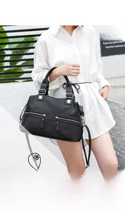 Detail of black pebbled leather tote featuring silver zippers and adjustable straps