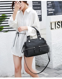 Detail of soft black leather tote featuring silver zippers and adjustable crossbody strap