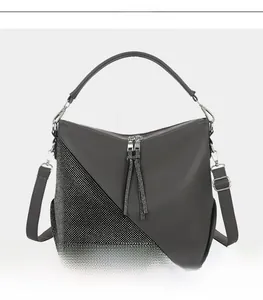 Detailed front view of grey leather handbag featuring rhinestone panel and long tassels