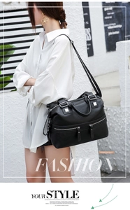 Close-up of black lychee-textured leather bag with silver zippers and reinforced handles