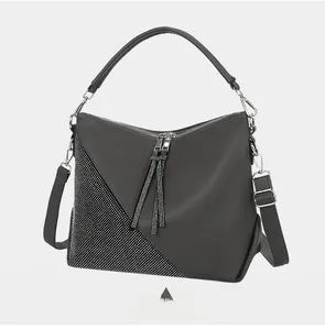 Detail view of grey faux leather handbag showing rhinestone inlay and dual tassel zippers
