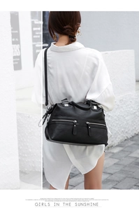 Outdoor street shot of a large black soft leather tote bag with silver zippers and straps