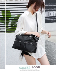 Close-up of black leather crossbody bag with multiple zippers and adjustable strap