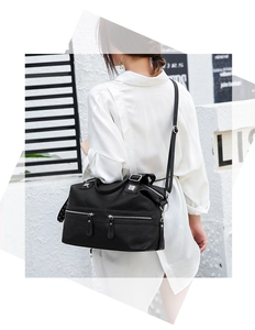 Model showing large black faux leather shoulder bag with decorative silver zippers