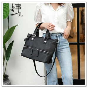 Detail of black faux leather tote with silver zippers and rivets on a fashion model